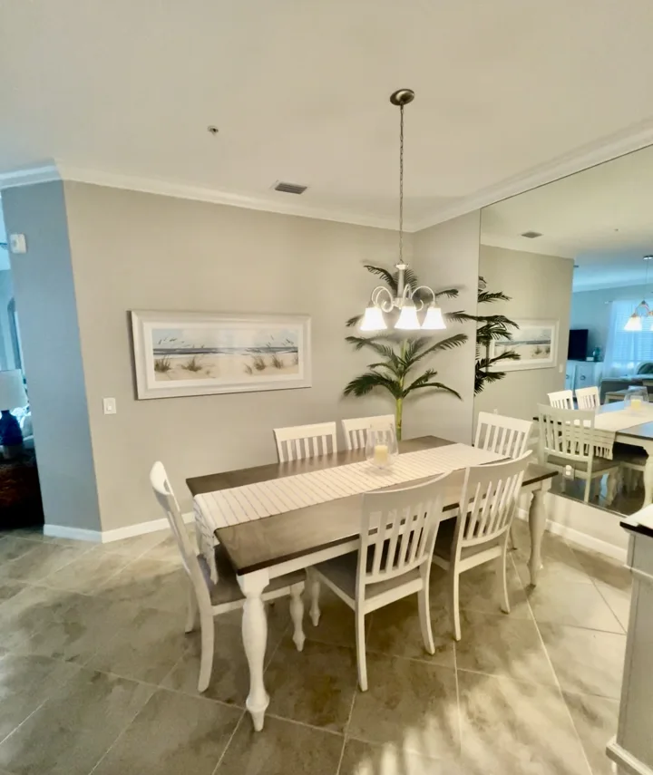 Dining area with a white and wood table, pale chairs, and mirrored wall
