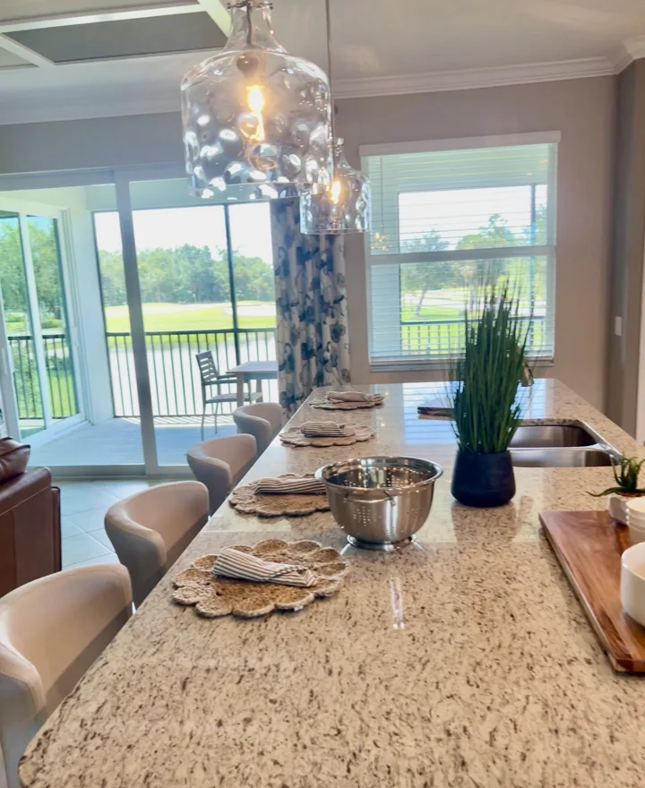 Kitchen island with pale upholstered stools and glass pendant lights
