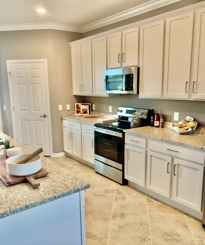 Bright kitchen with white cabinetry, stone counters, and stainless steel appliances