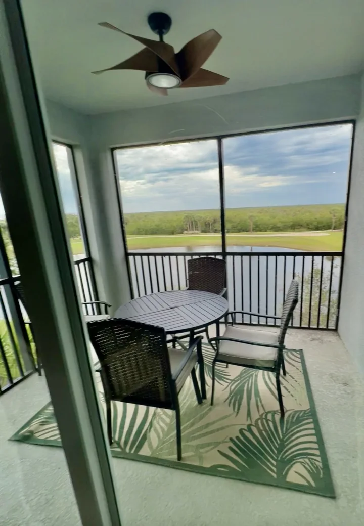 Screened balcony with a dining table and a water and landscape view